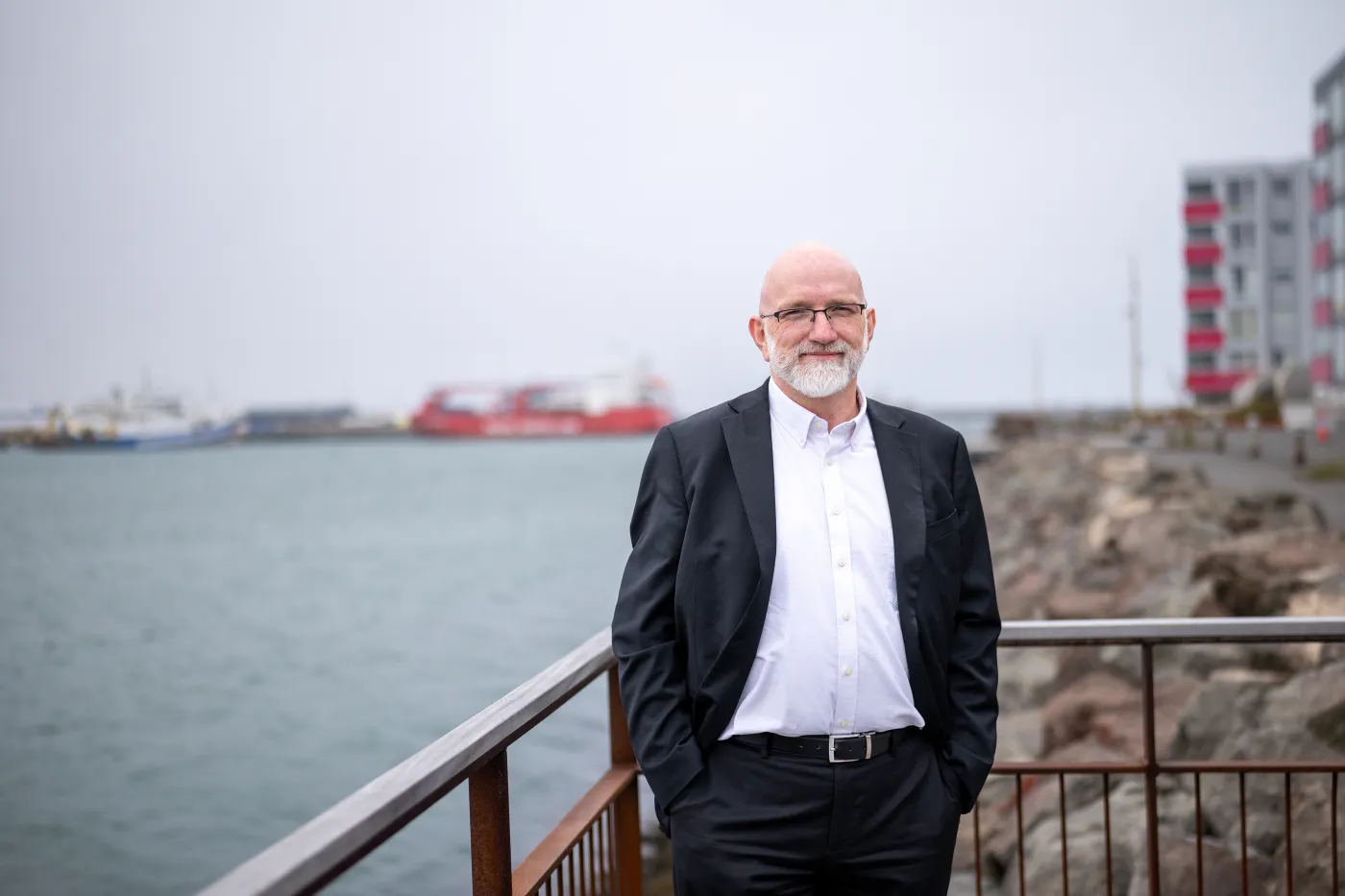 Gísli standing by the harbor, hands in pockets